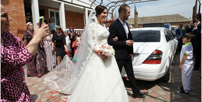 Брат жениха ведет невесту к свадебному кортежу